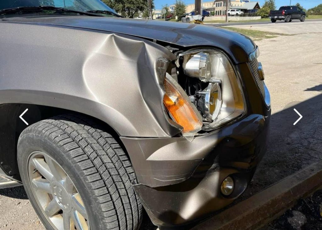 Car with a dented front panel and broken headlight.